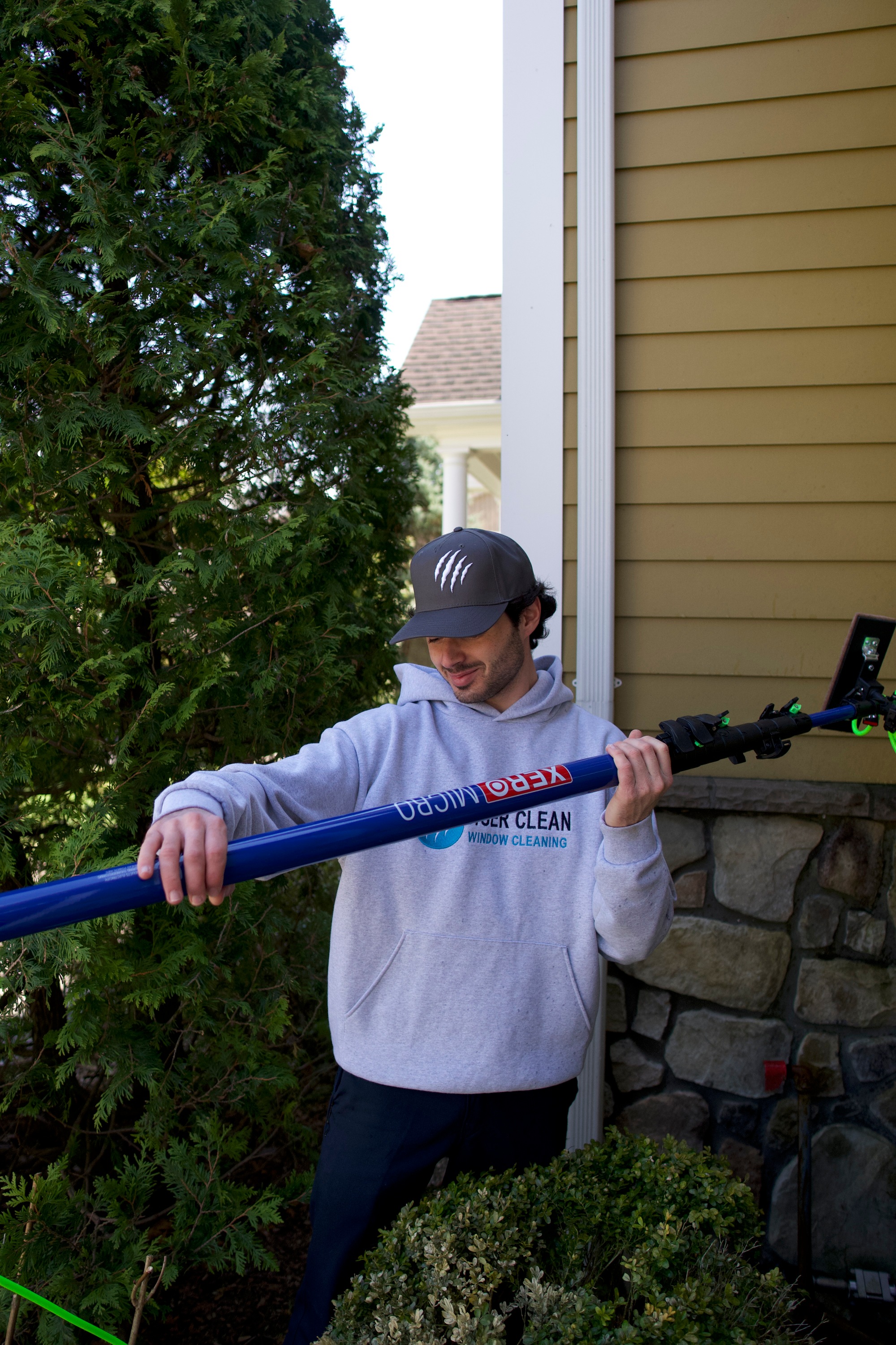 Tiger Clean technician with a water-fed pole outside a home