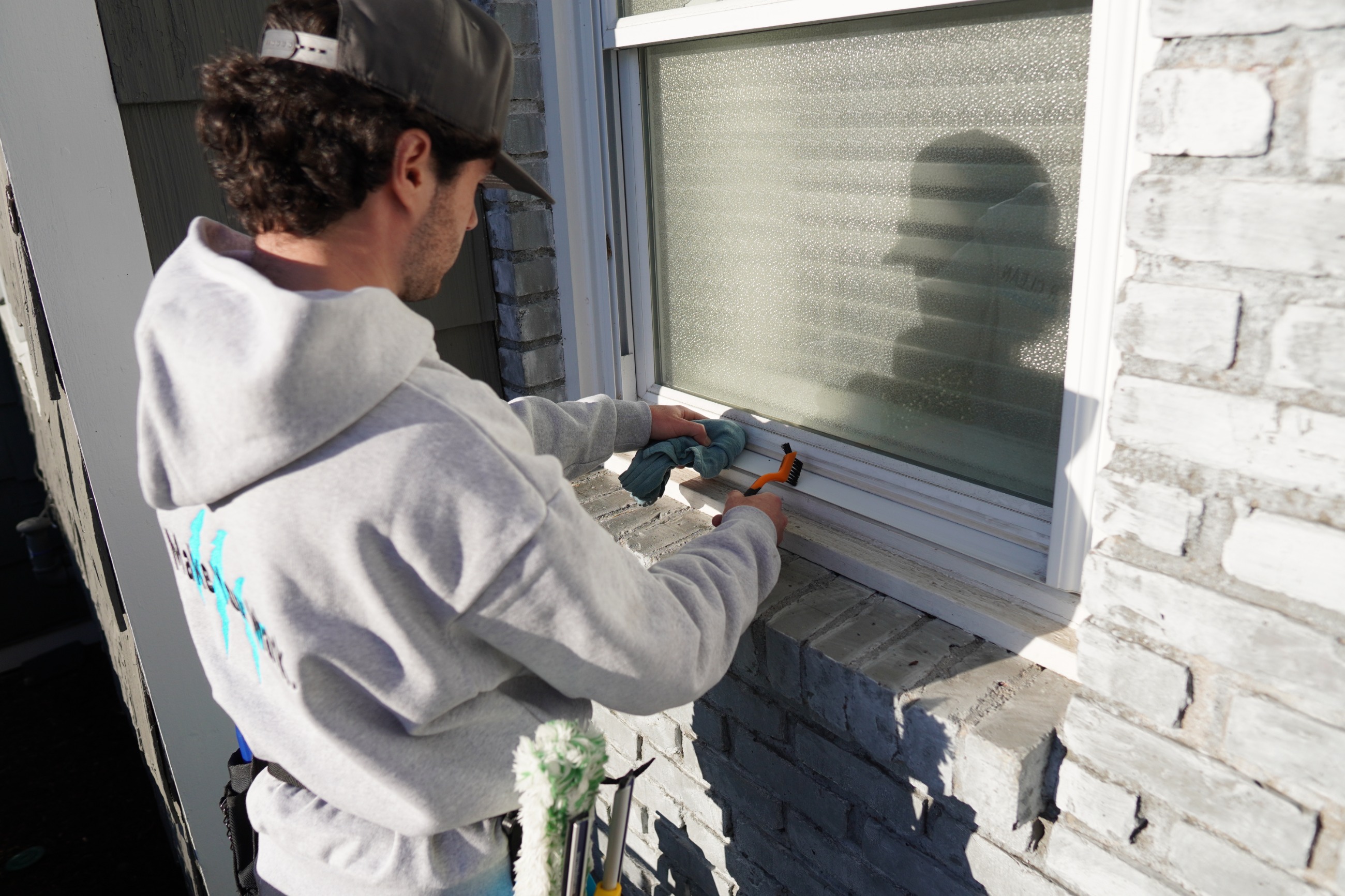 Tiger Clean technician detailing a window track with a brush